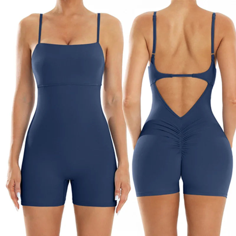 A woman models a navy blue backless fitness jumpsuit from the rear view.