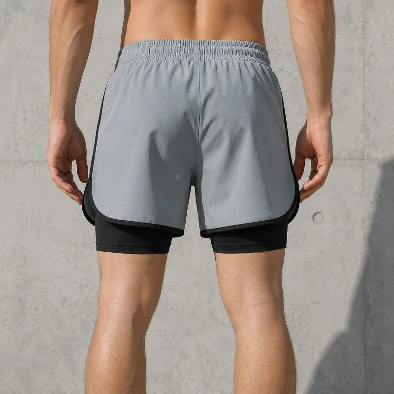A man is wearing gray athletic shorts with black trim, showing the fit and features.