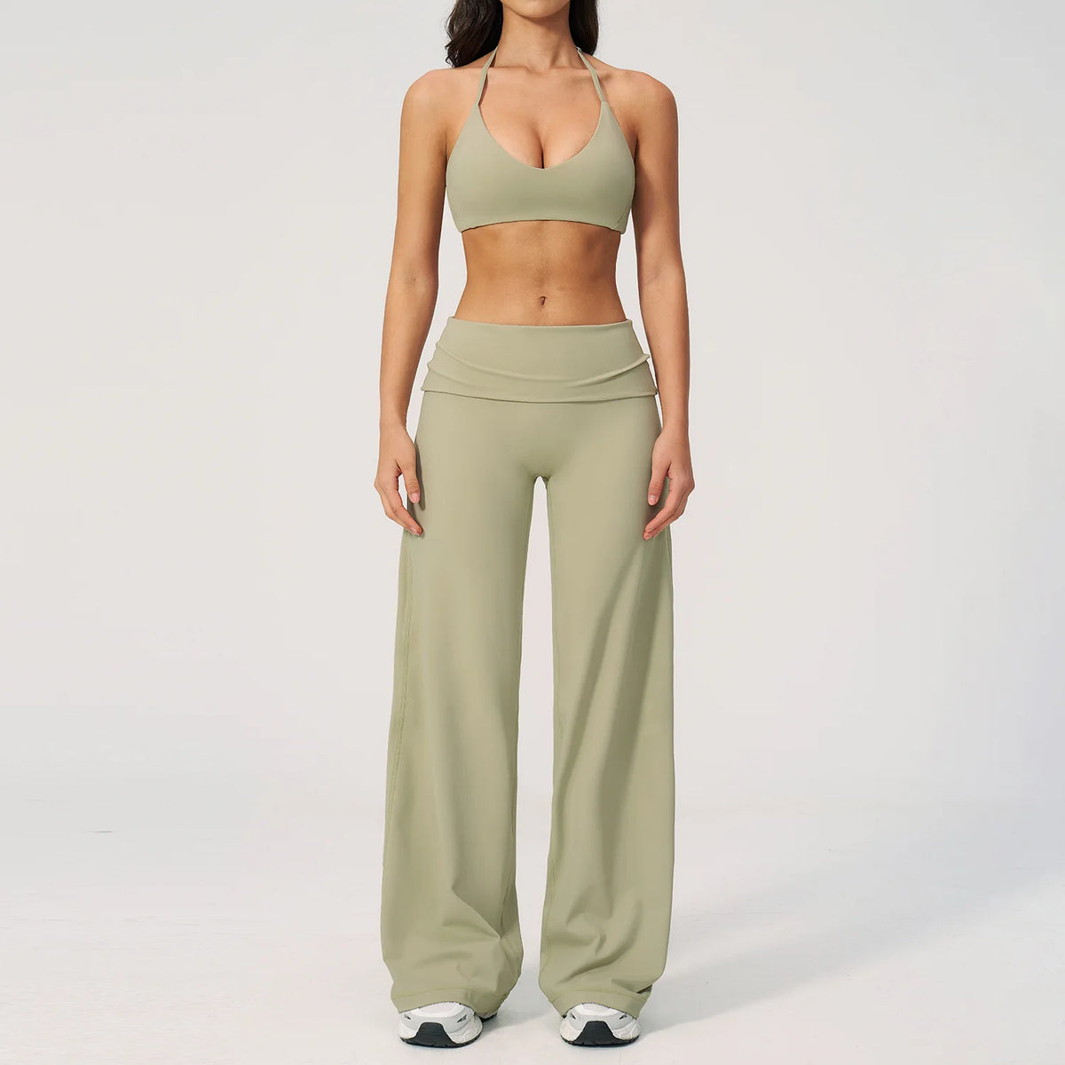 A woman wearing a light olive green women's premium fitness tracksuit top and matching high-waisted pants.