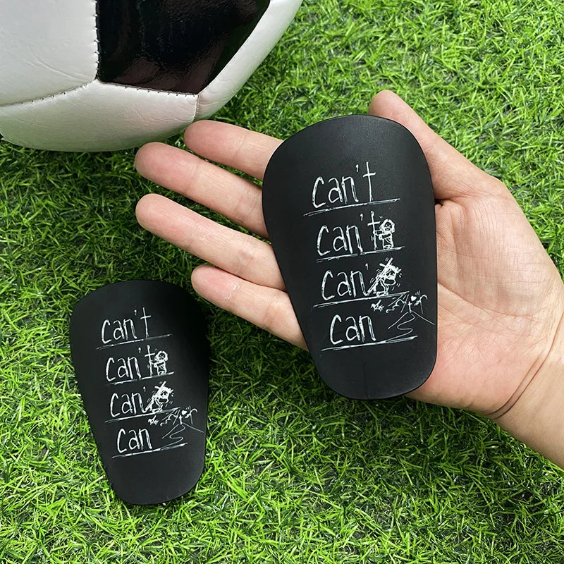 A hand holds a black silicone mini wear-resistant shin guard with the text Can't Can I Can