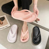 A person is holding a pink comfort platform flip flop and a black flip flop on a light surface.