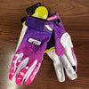 A pair of purple and pink durable riding gloves for motorcycle and off-road sports are displayed on a wooden surface.