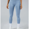 A woman wearing light blue high-waist yoga leggings and white socks standing against a plain background.