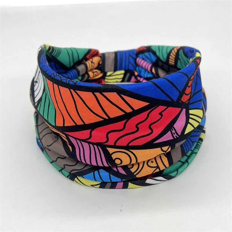 A colorful bohemian stretch cotton headband featuring abstract floral and geometric patterns in shades of orange, pink, blue,