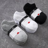 A collection of black and white breathable men's sports ankle socks are displayed on a gray surface.