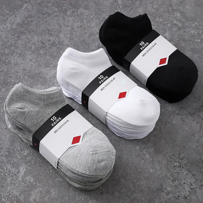 A collection of black and white breathable men's sports ankle socks are displayed on a gray surface.