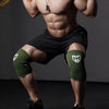 A muscular man wearing green compression knee sleeves while posing for a gym photo.