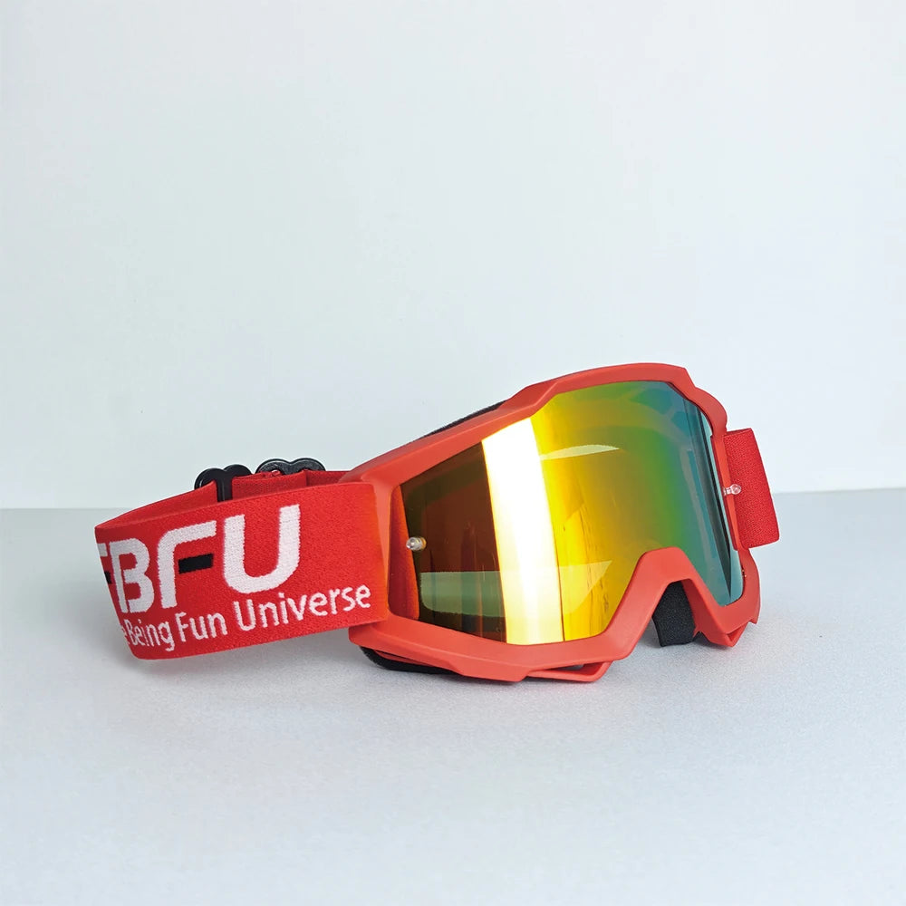A pair of red sport-grade skiing goggles with orange tinted lenses resting on a white surface.