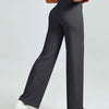 A woman models high waisted gray yoga pants while standing.