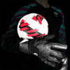 A black long-sleeved shirt shows a hand wearing black latex goalkeeper gloves gripping a white and red soccer ball.