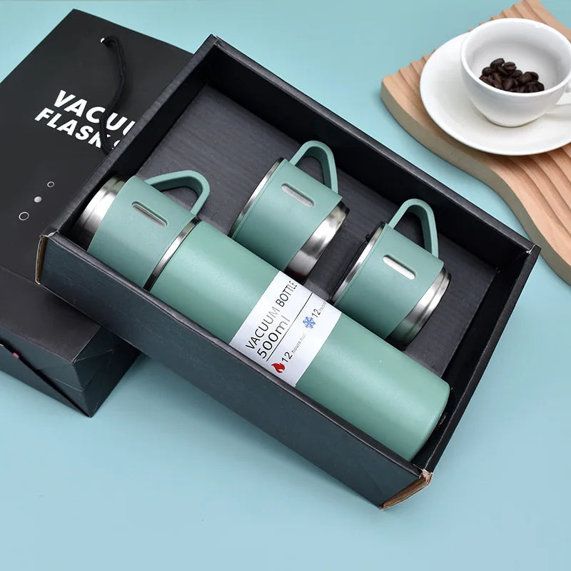 A dark box contains a light green stainless steel vacuum flask and accessories on a wooden surface.