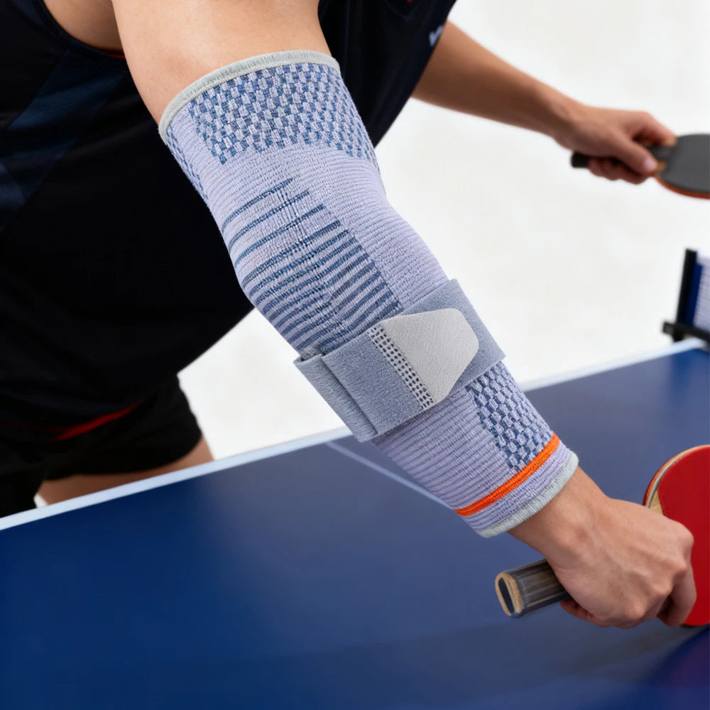 Person wearing a gray elbow compression sleeve with a gel pad for joint support while playing table tennis.