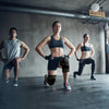 Three individuals exercising in a gym setting wearing copper knee braces.