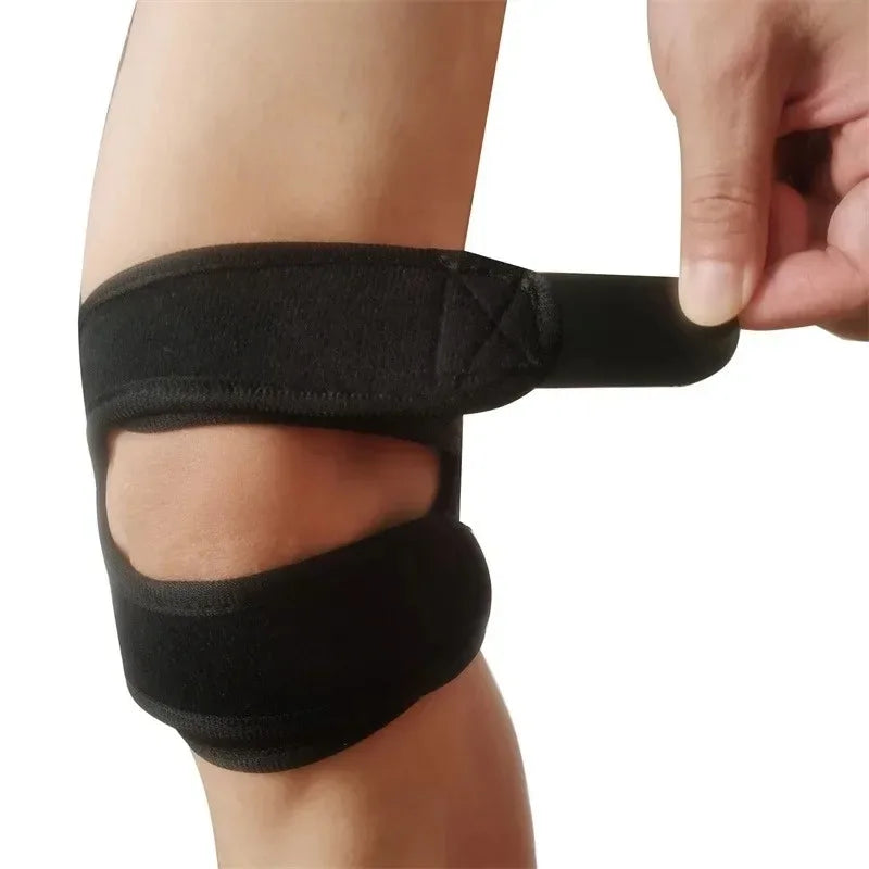 A hand is putting on a black pressurized knee support sleeve for sports on a person's leg.