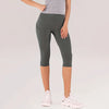 Una persona modelando leggings capri de yoga verde oliva de cintura alta y zapatillas deportivas blancas.