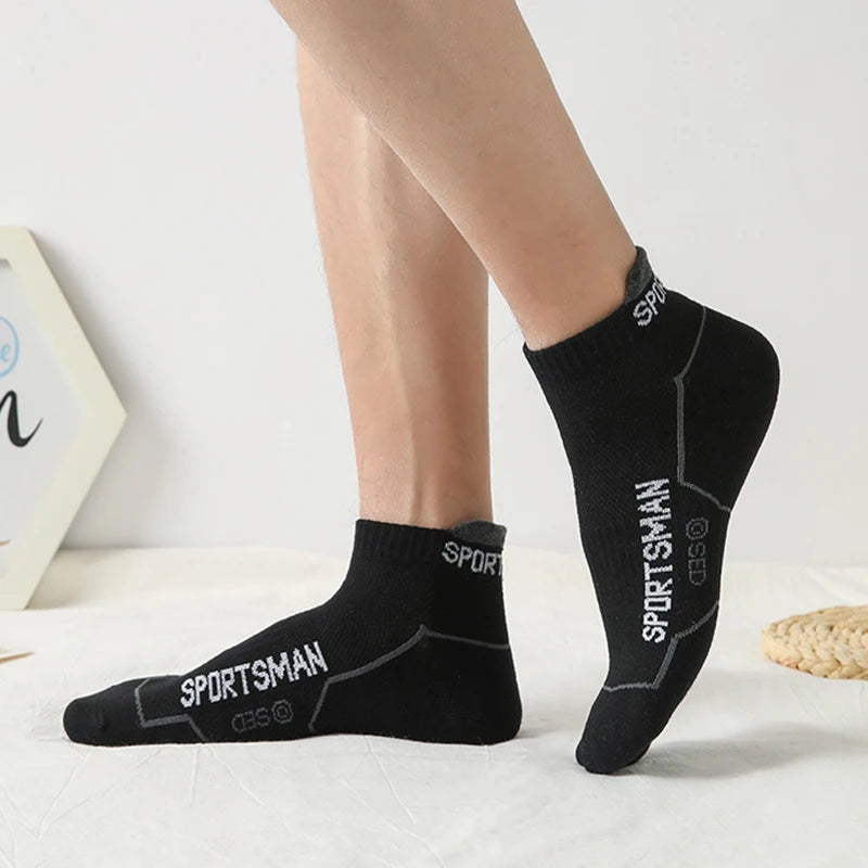 Black men's athletic socks with the Sportsman logo worn on a person's foot.