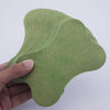 A hand holds a light green self-heating lumbar spine patch, showing its contoured shape.
