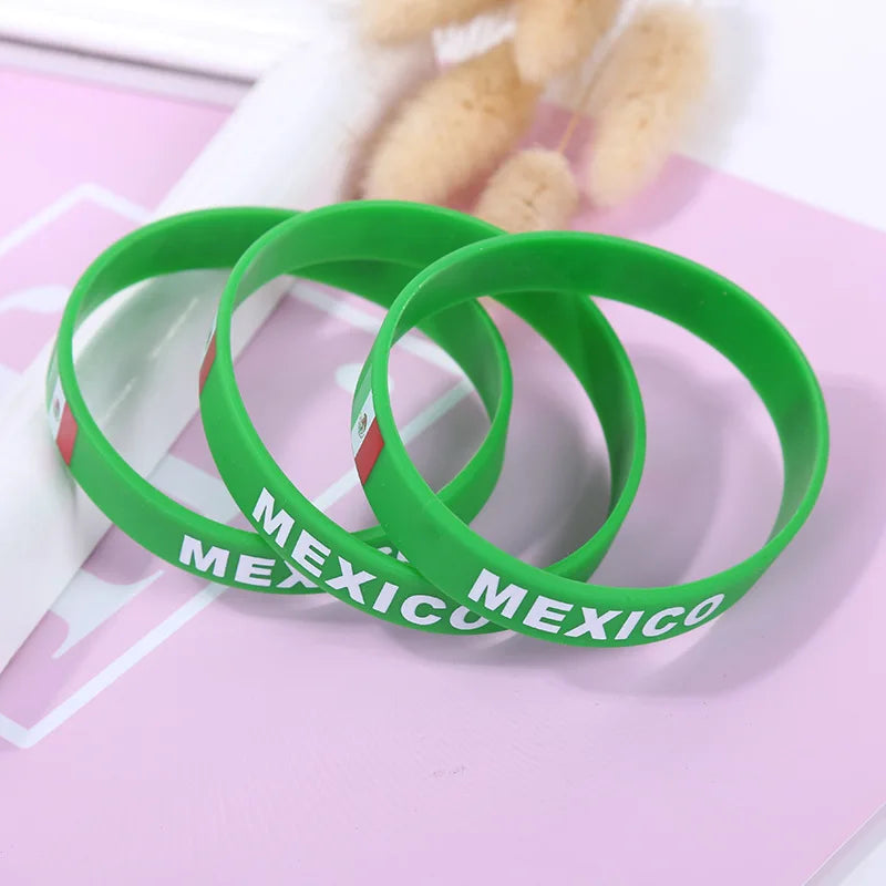 Green silicone wristbands with Mexico text displayed on a pink background.