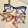 A hand holds a pair of vintage color block blue light blocking eyewear with tortoiseshell frames and clear lenses.