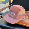 A pink breathable quick-dry baseball cap with embroidered text resting on a dark surface.