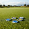 Four precision golf ball markers and slope meters are placed on a green golf course fairway.