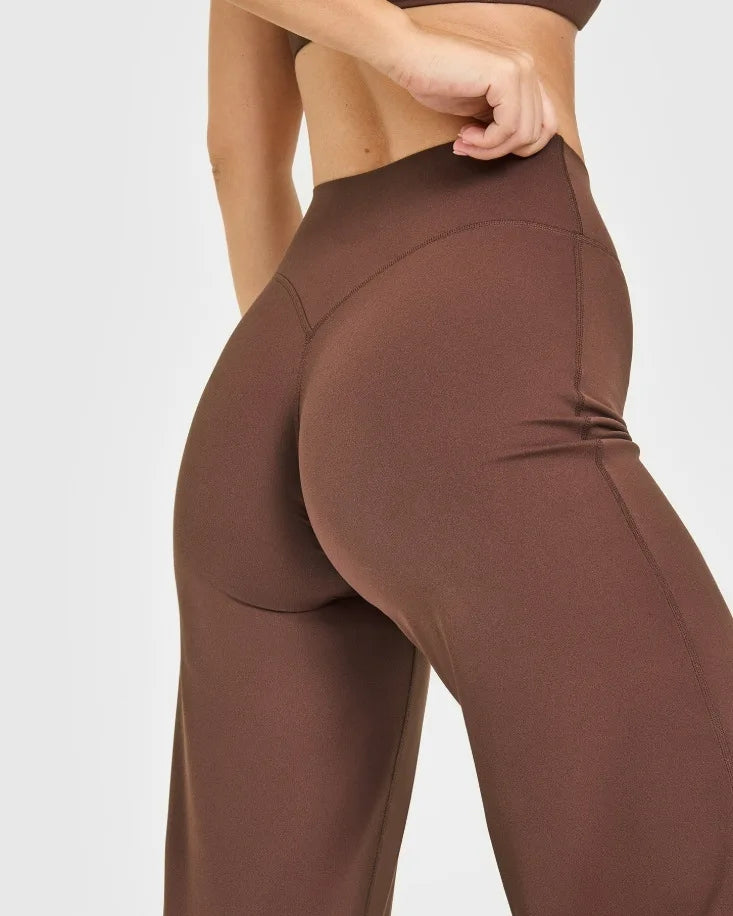 A close-up of a model wearing high-waist yoga pants in a brown color.