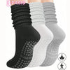 A set of three pairs of black, white, and gray silicone Pilates and yoga socks shown vertically.