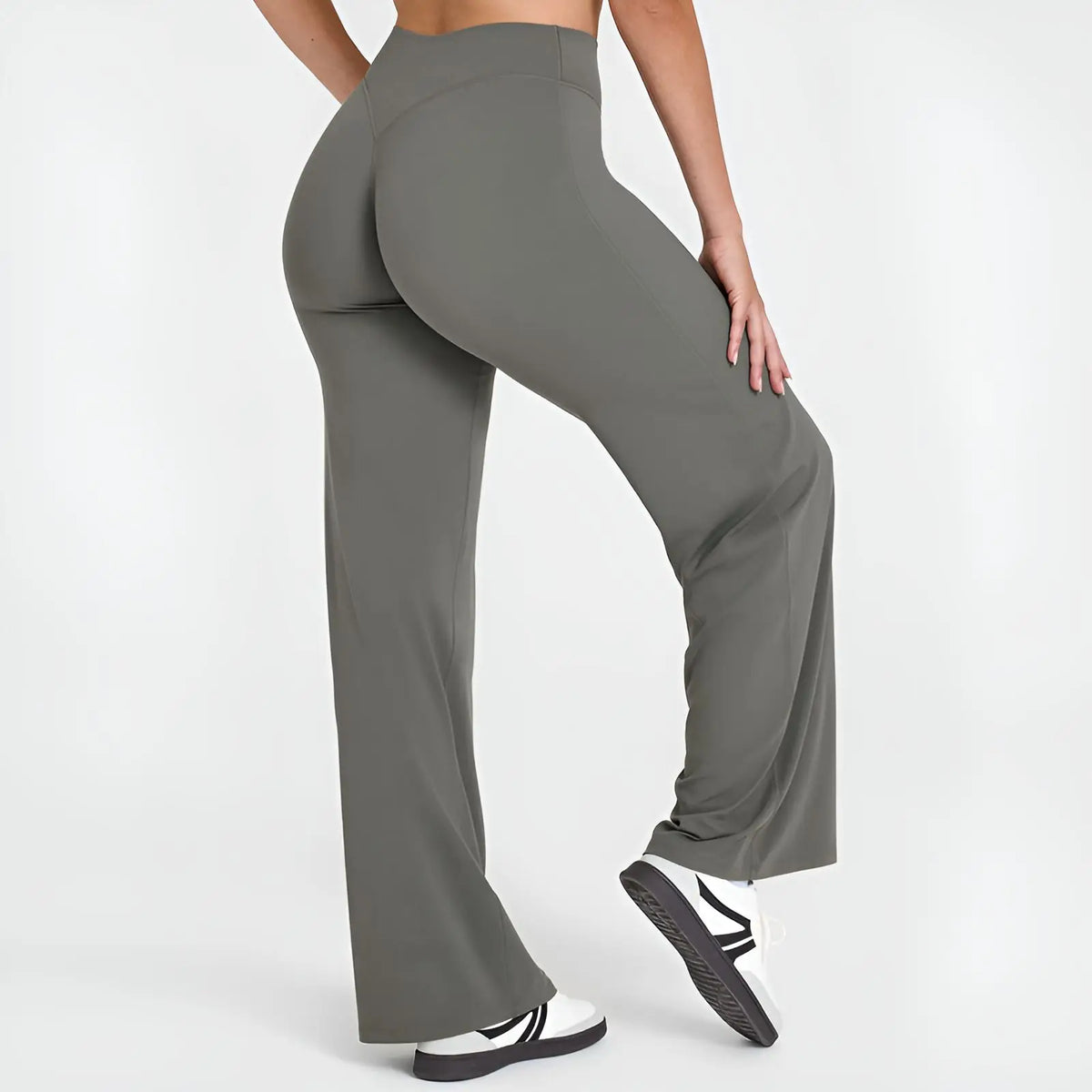 A person wearing dark gray high-waist yoga pants and white sneakers.