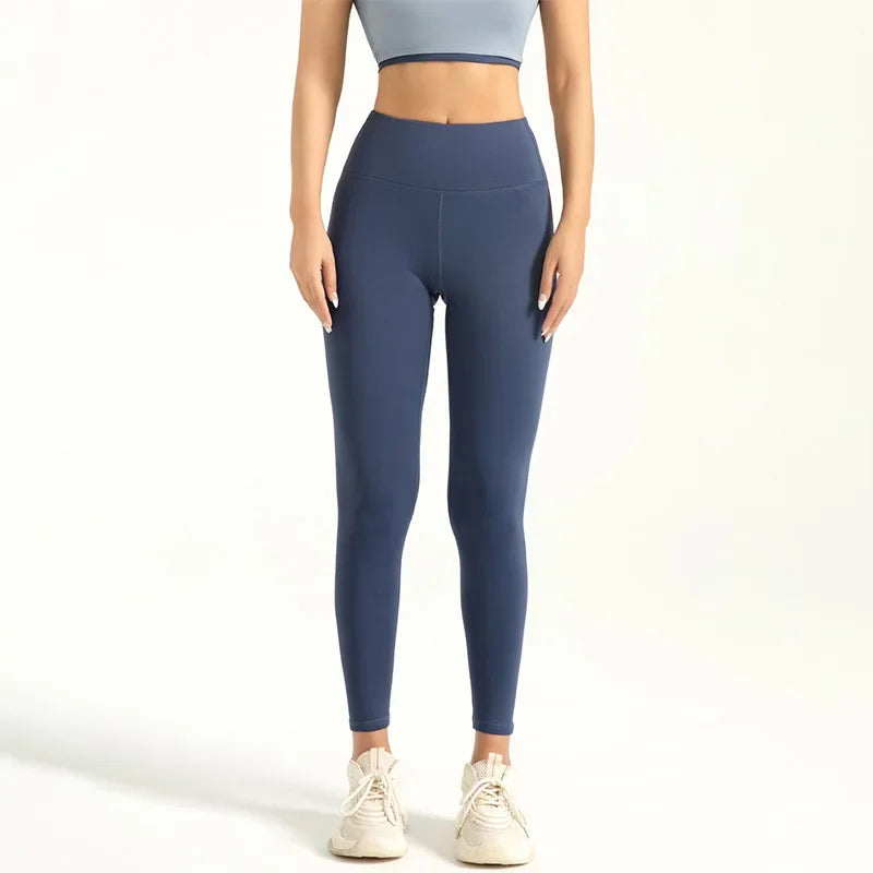 A person wearing dark blue seamless high-waist yoga leggings and a light gray cropped top.