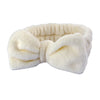 A white microfiber spa headband and wristband set folded and displayed against a white background.