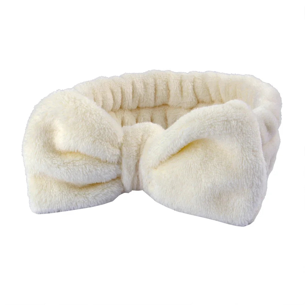 A white microfiber spa headband and wristband set folded and displayed against a white background.