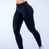 Una persona vistiendo leggings de yoga negros sin costuras y de cintura alta, de pie contra un fondo blanco.