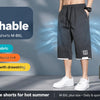 A person wearing dark gray breathable loose fit summer shorts with a black wristband and white sneakers.