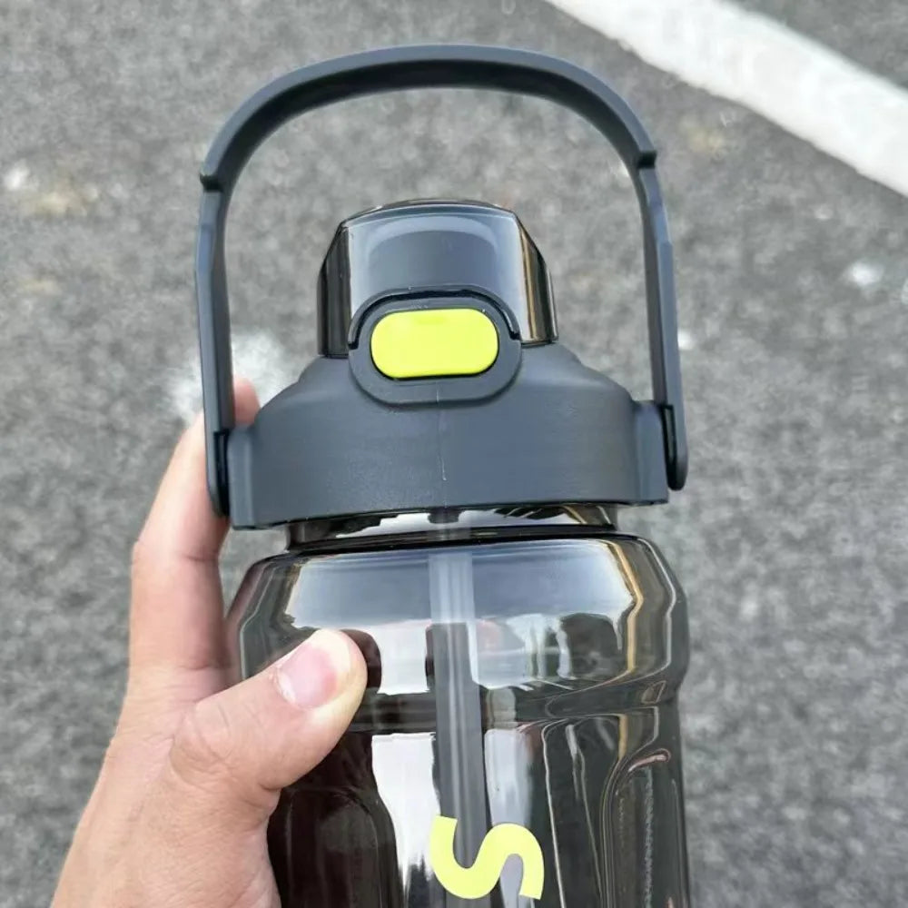 A hand holds a black insulated sports water bottle with a yellow cap and a silver straw.