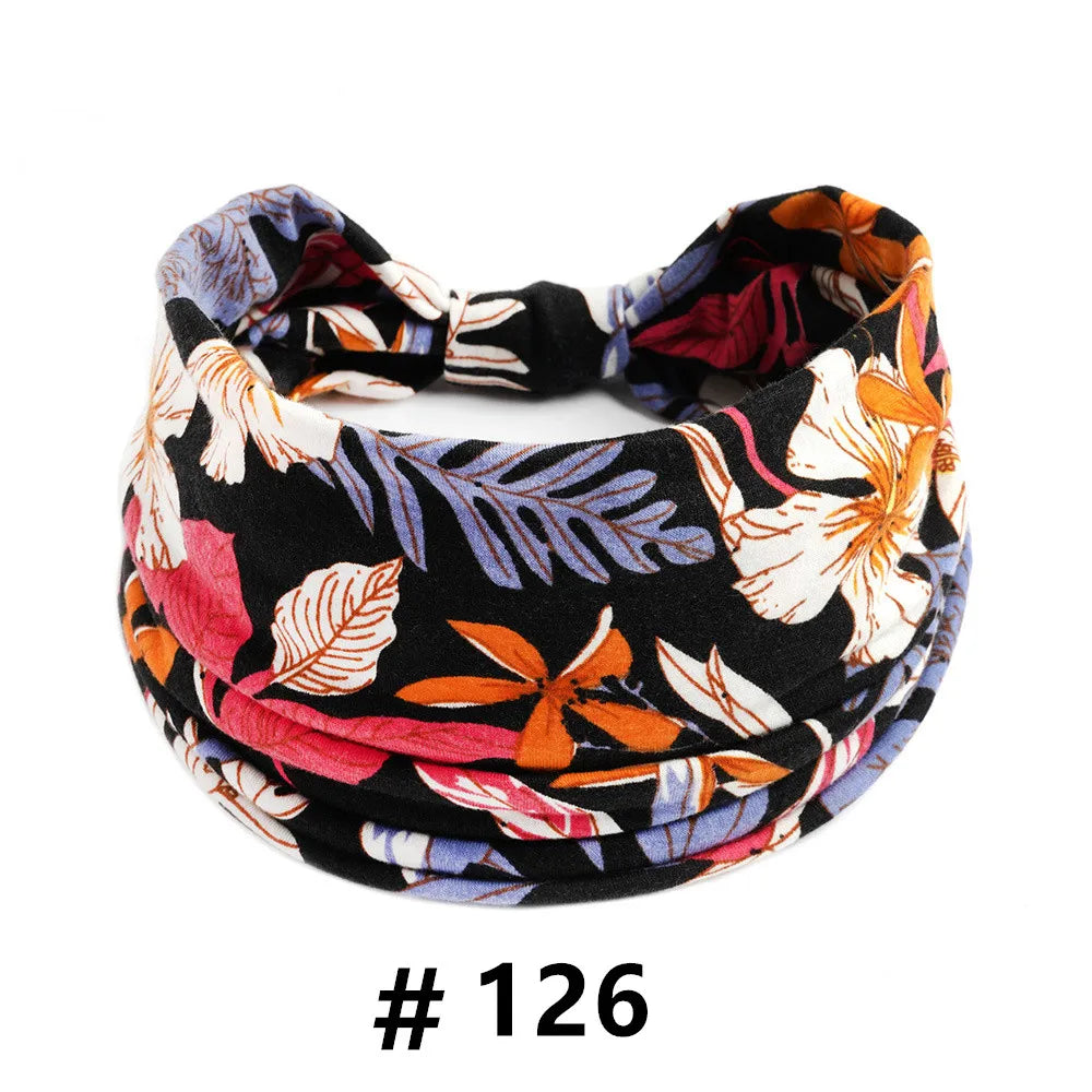 Bandeau en tissu à motifs floraux et feuillages noirs, orange, rose et violet.