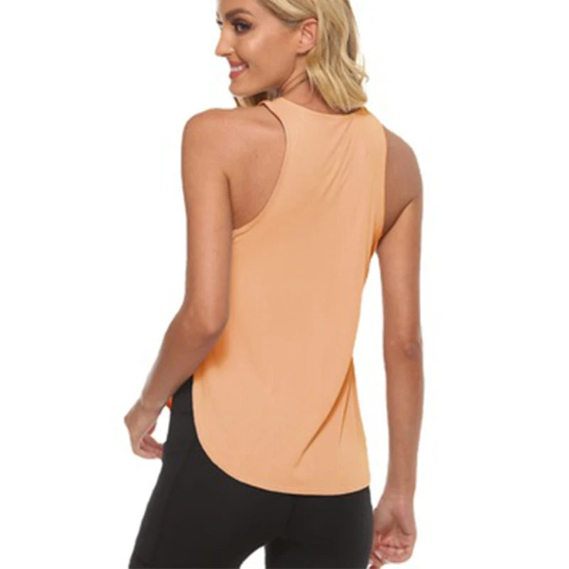 A woman wearing a peach-colored quick-dry yoga and gym tank top and black leggings.