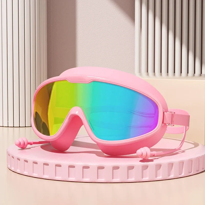 Gafas de natación antiempañante rosas con lente arcoíris vibrante sobre un soporte circular rosa claro.