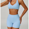 A woman models a light blue padded sport yoga bra and matching bottoms.