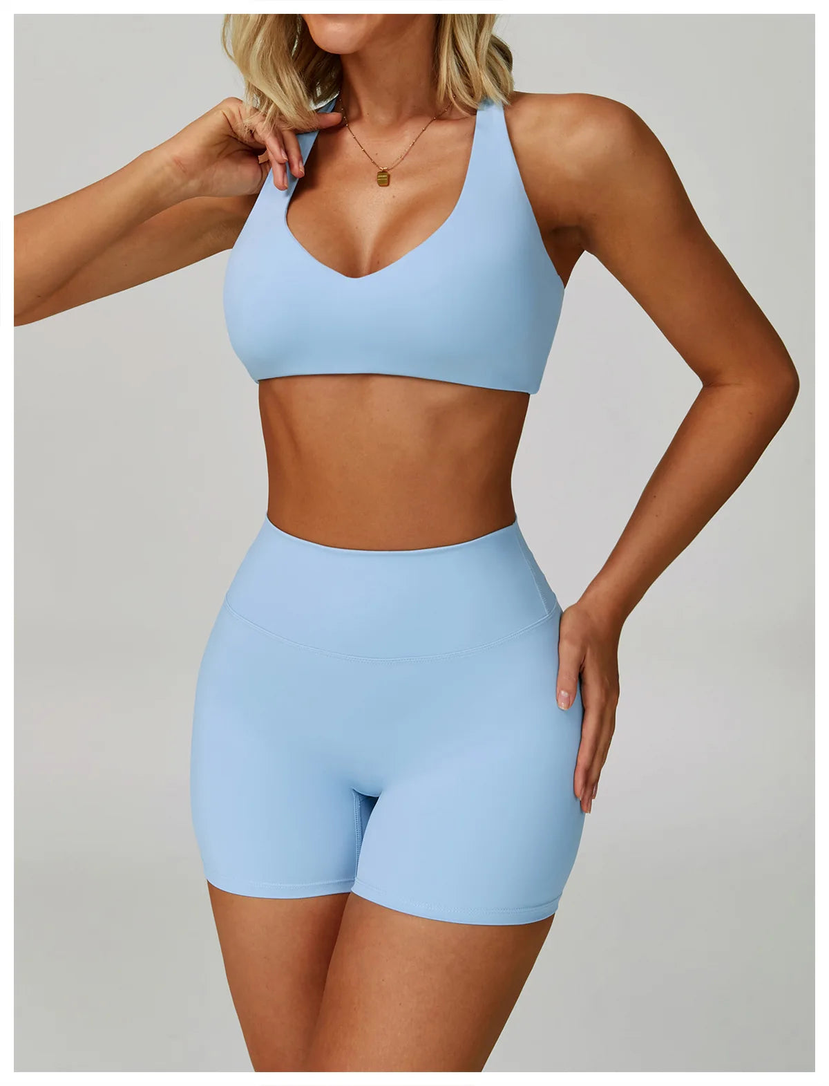 A woman models a light blue padded sport yoga bra and matching bottoms.
