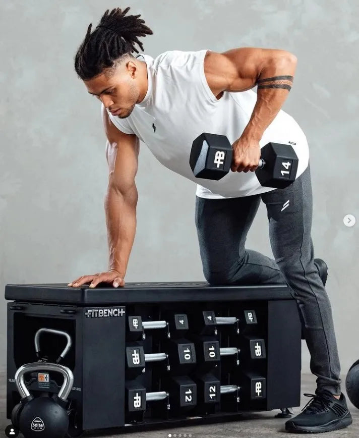 Muskulöser Mann trägt ein weißes ärmelloses Fitness-Shirt und führt eine Gewichtheberübung mit schwarzen Hanteln aus.