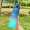 A hand holds a gradient blue insulated sports water bottle outdoors on a grassy area.