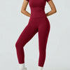 Eine Frau trägt ein dunkelrotes Yoga-Set mit hohen Bund-Leggings und einem kurzen Top.