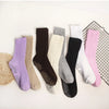 A collection of mid-calf yoga and pilates socks in various colors including purple, beige, gray, black, and white.