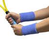 A hand is holding a yellow and black sports whistle while wearing two purple wristbands for sweat absorption.