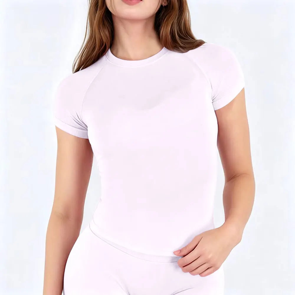 A woman wearing a light pink performance fitness short sleeve top and matching bottoms.