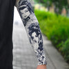 Close-up of a person's arm displaying intricate black and gray traditional Asian-style tattoo sleeve designs.