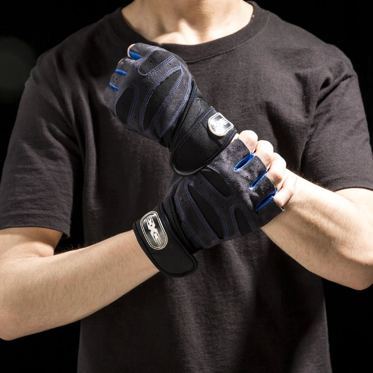 A person wearing black t-shirt is holding a black performance weightlifting grip glove.
