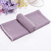 Serviette ronde violette roulée à côté d'une serviette plate violette sur fond blanc.