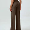 A woman is modeling high waisted brown yoga pants with a white top.