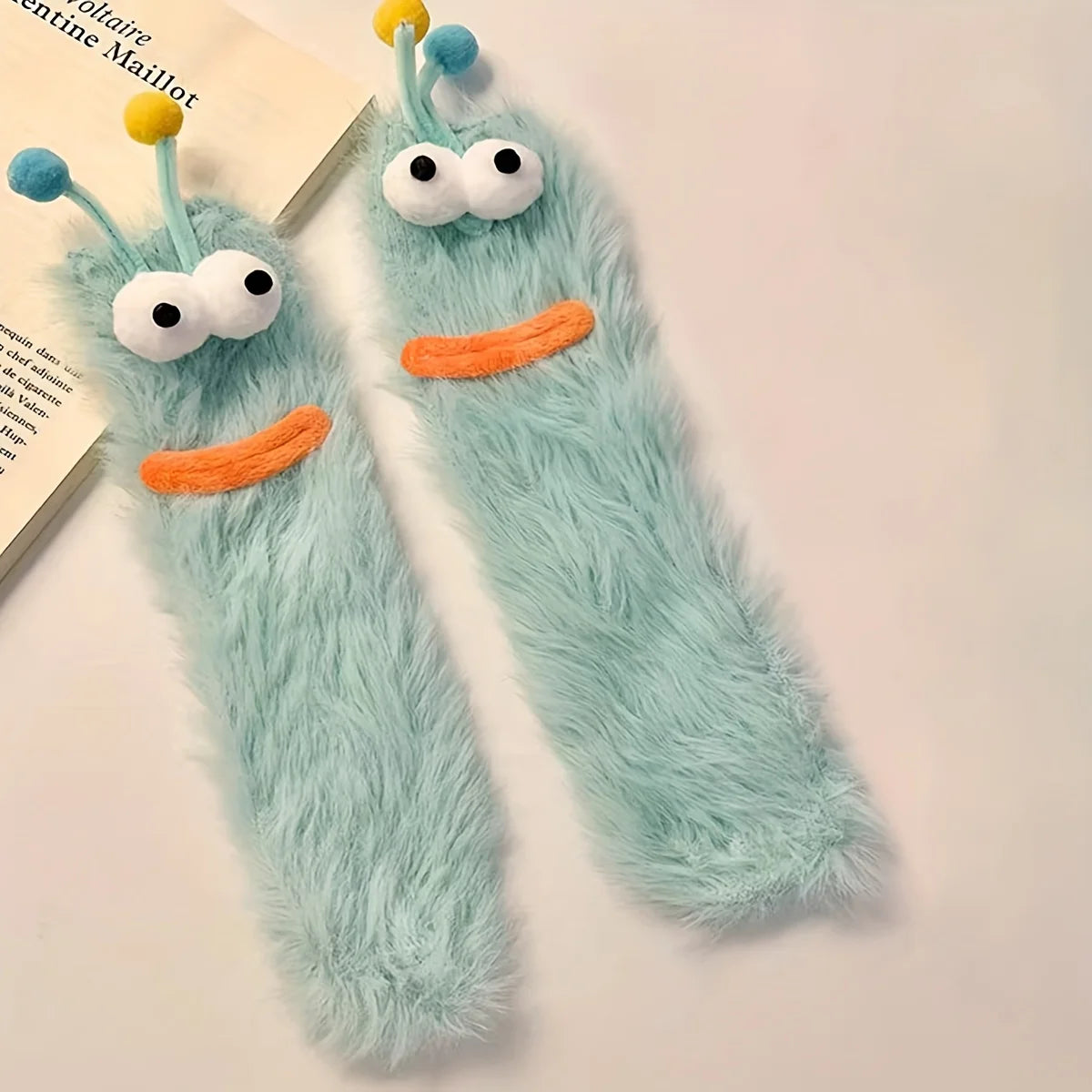 Pair of funny plush caterpillar floor socks with blue fuzzy body and orange feet